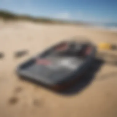 Kitesurfing gear laid out on sandy beach with waves in the background