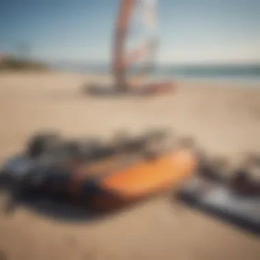 Windsurfing gear laid out on a sandy beach